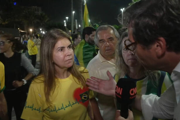 Apoiadores de Jair Bolsonaro com a camiseta do Brasil ao lado do repórer da CNN Portugal