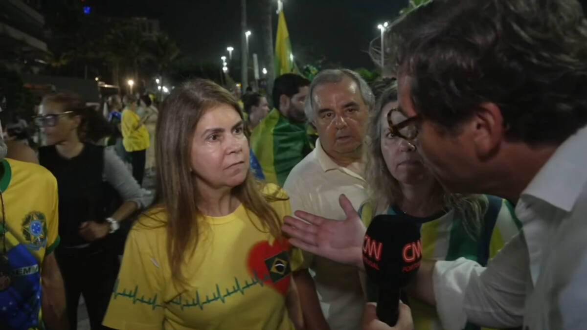 Apoiadores de Jair Bolsonaro com a camiseta do Brasil ao lado do repórer da CNN Portugal