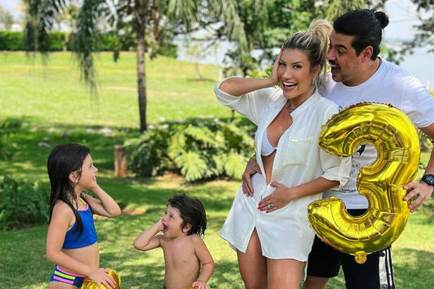 Cristiano ao lado da esposa e dos dois filhos menores, segurado balões dourados com os números 1, 2 e 3