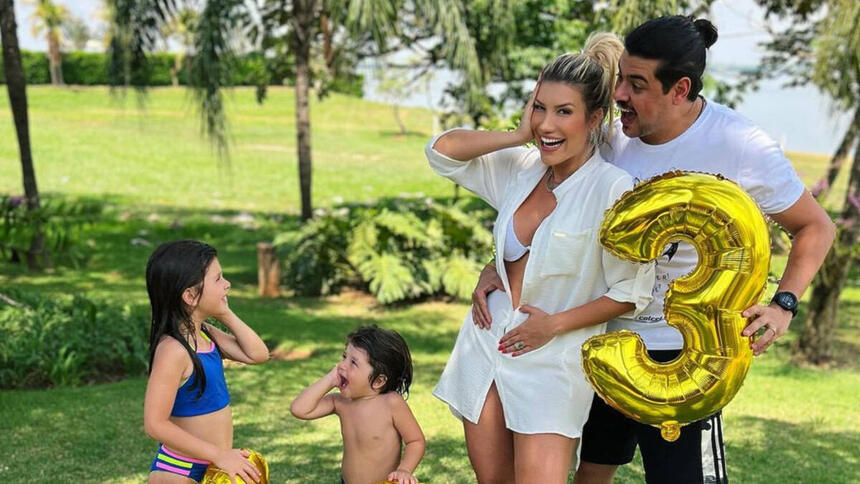 Cristiano ao lado da esposa e dos dois filhos menores, segurado balões dourados com os números 1, 2 e 3