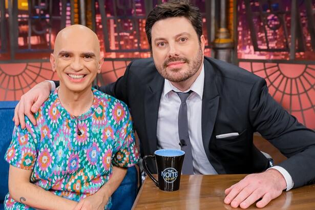 Edson Cordeiro sorrindo, de camisa estampada ao lado de Danilo Gentili durante gravação do The Noite, do SBT