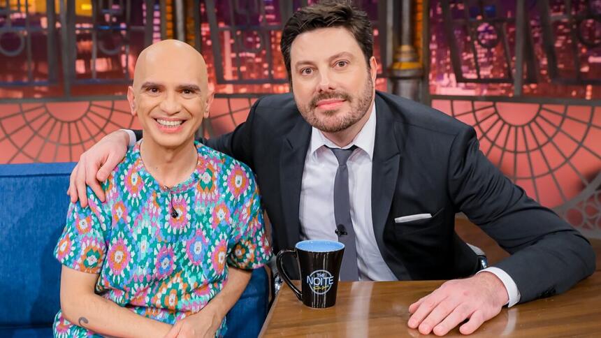 Edson Cordeiro sorrindo, de camisa estampada ao lado de Danilo Gentili durante gravação do The Noite, do SBT