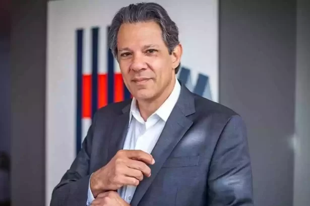 Fernando Haddad de palitó cinza, camisa social branca ajeitando a gravata