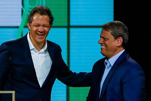 Fernando Haddad sorrindo com a mão no ombro de Tarcisio de Freitas durante debate