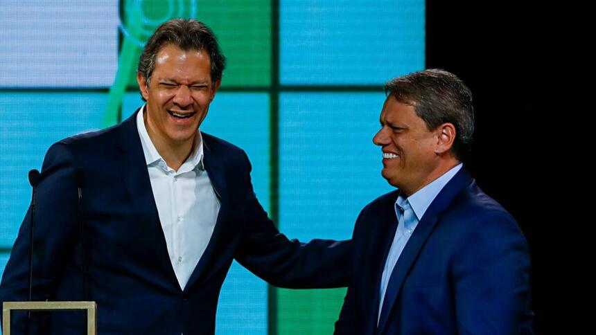 Fernando Haddad sorrindo com a mão no ombro de Tarcisio de Freitas durante debate