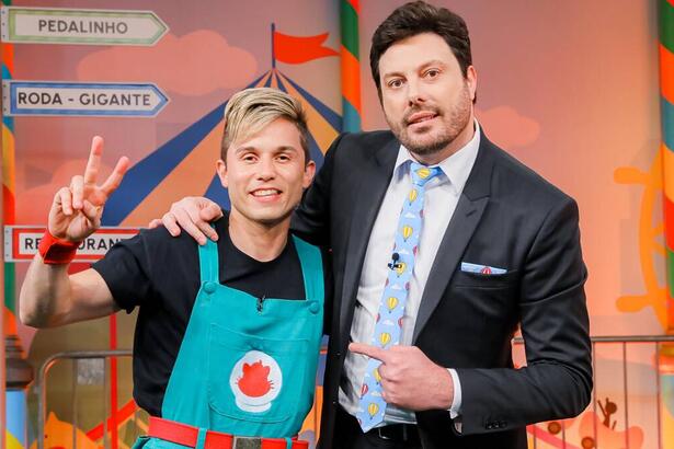 Gato Galáctico de macacão verde e camisa preta sorrindo ao lado de Danilo Gentili durante gravação do The Noite, do SBT