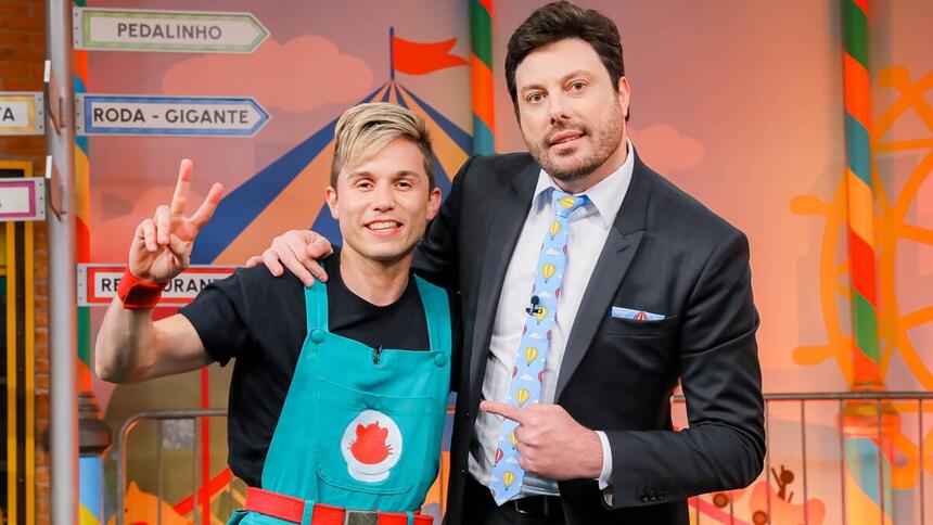 Gato Galáctico de macacão verde e camisa preta sorrindo ao lado de Danilo Gentili durante gravação do The Noite, do SBT