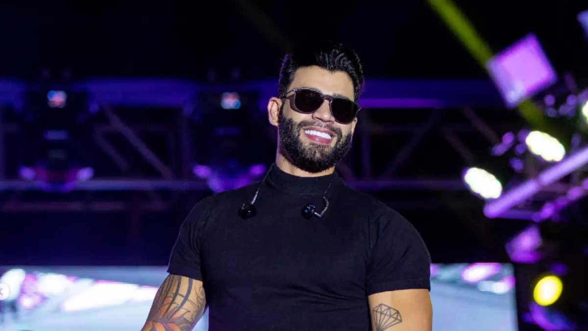 Gusttavo Lima de óculos escuros encima de um palco em um show