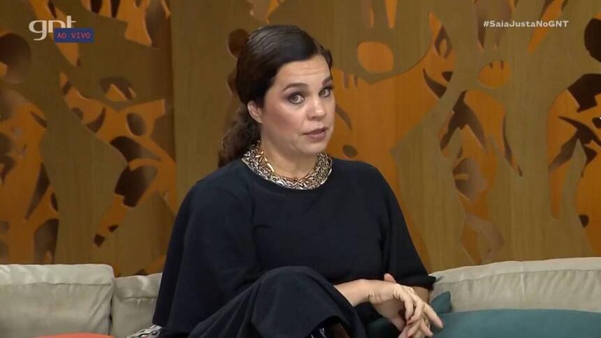 Isabel Teixeira sentada no sofá do Saia Justa, em trecho da entrevista