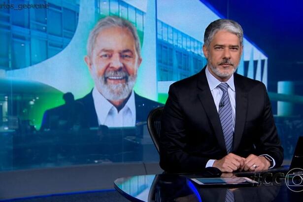 William Bonner sentado na bancada com Lula na projeção do Jornal Nacional, da TV Globo