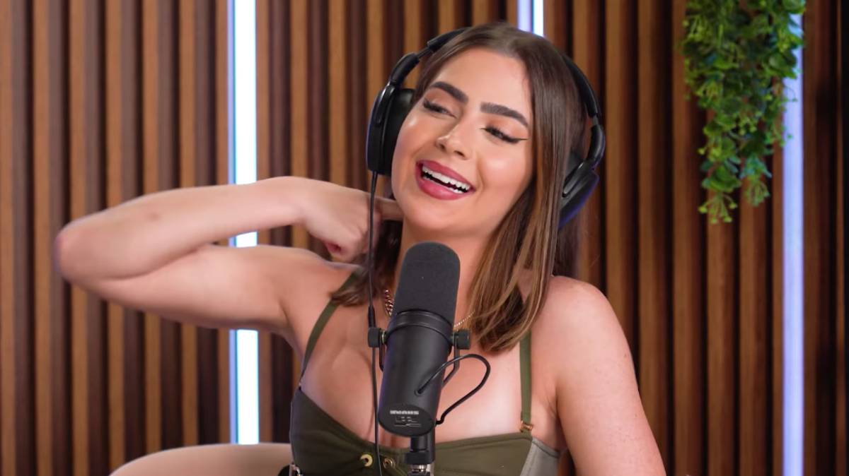 Jade Picon de camisa verde, mão no ombro, sorrindo durante entrevista ao Quem Pode Pod