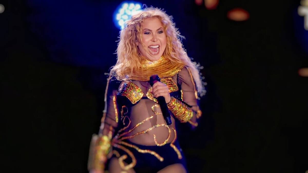 Joelma com a boca aberta segurando o microfone com a mão esquerda durante show