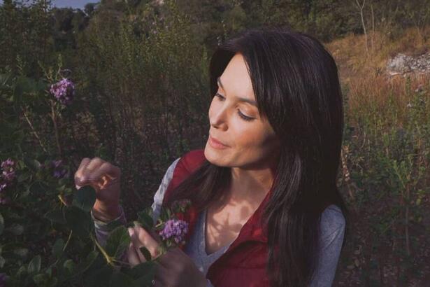 Liliana Junger próximo a um jardim de plantas, em trecho do Globo Repórter