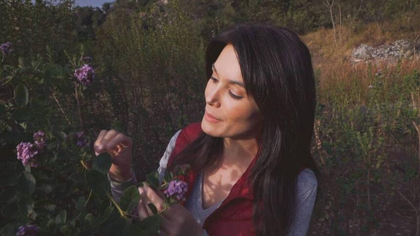 Liliana Junger próximo a um jardim de plantas, em trecho do Globo Repórter