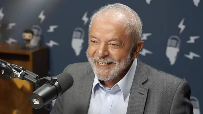 Lula de blazer cinza e camisa social branca sorrindo, sentado