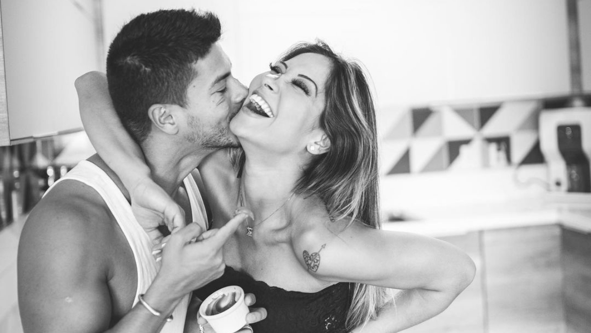 Maíra Cardi de top preto, sorrindo, abraçando Arthur Aguiar de regata branca