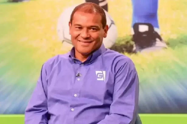 Muller de camisa social azul, sentado, sorrindo durante entrevista