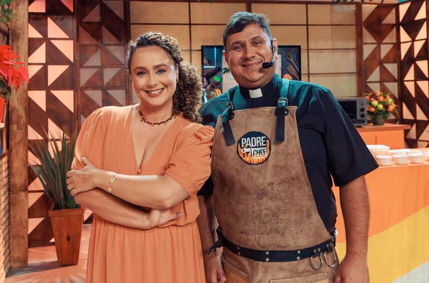 Padre Chef Evandro e Letícia Andrade de vestido marrom, sorrindo, com braços cruzados durante gravação de Sabor de Vida, da TV Aparecida