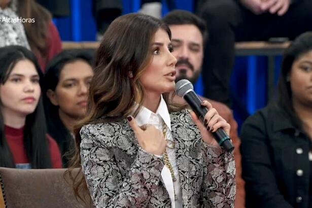 Paula Fernandes de blazer e camisa social, sentada, durante gravação do Altas Horas