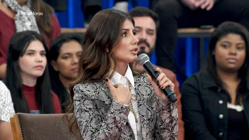 Paula Fernandes de blazer e camisa social, sentada, durante gravação do Altas Horas