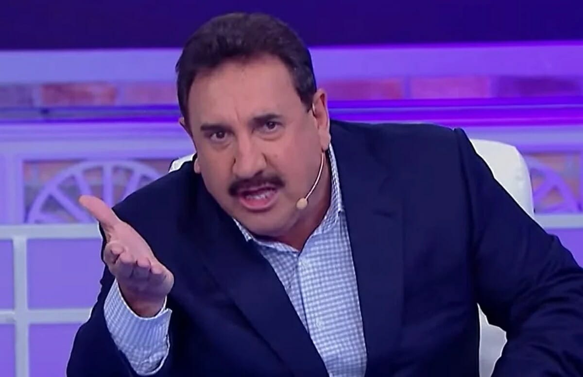 Ratinho de blazer azul escuro estendendo a mão durante gravação do seu programa no SBT