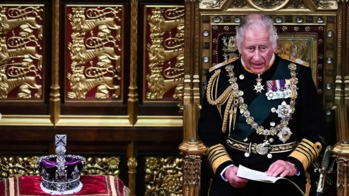 Rei Charles III sentado no trono, ao lado da coroa