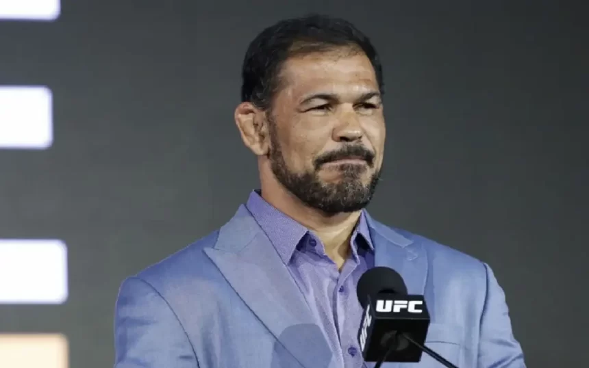 Rodrigo Minotauro de camisa social azul, usando barba e bigode, com semblante sério em apresentação do UFC