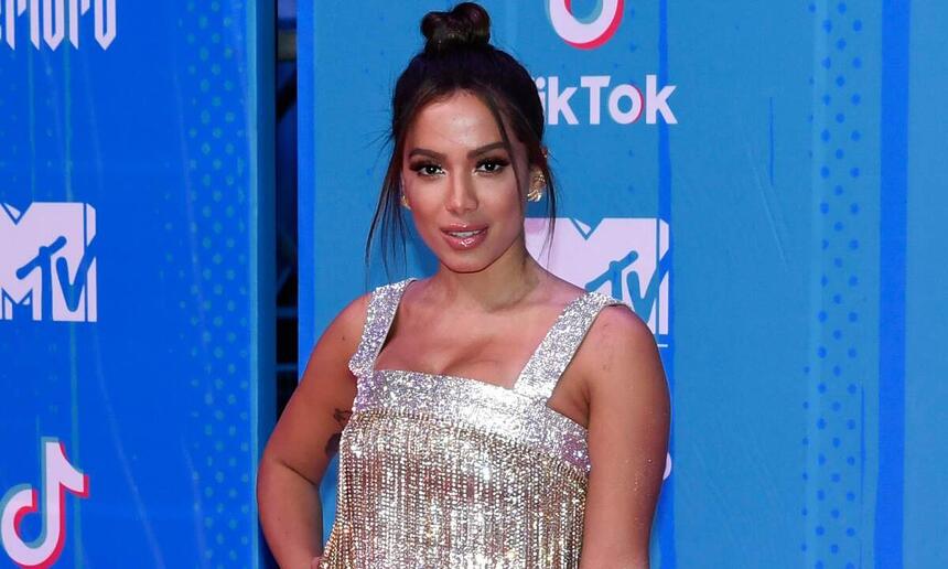 Anitta de vestido prata brilhoso, com cabelo preso e mão na cintura no redcarpet do MTV EMA 2021