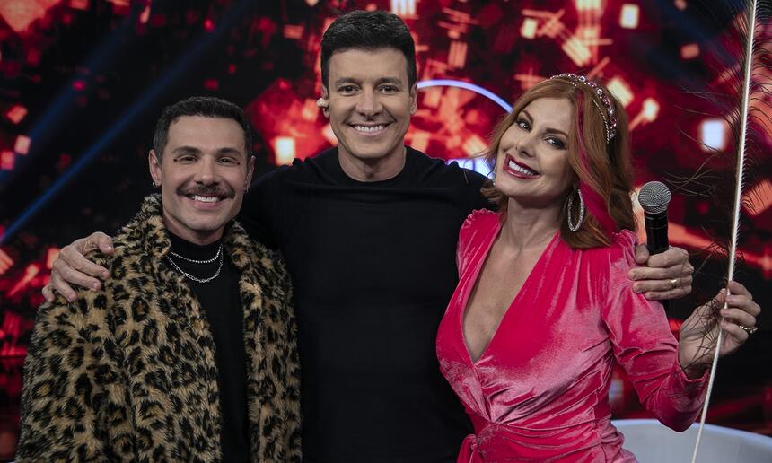 Alex, Rodrigo Faro e Deborah abraçados e sorridentes durante gravação do Hora do Faro