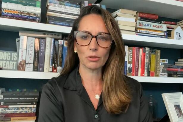 Ana Paula Henkel em trecho de um vídeo, com uma enorme estante de livros ao fundo