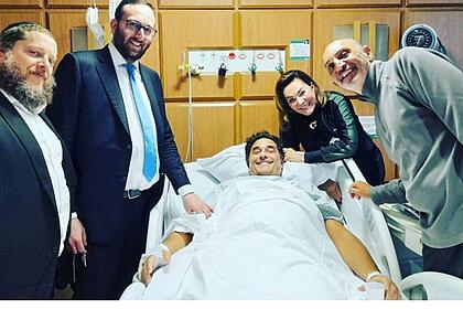 Luciano Szafir deitado na cama de hospital, ao lado dos médicos e da mãe Beth Szafir
