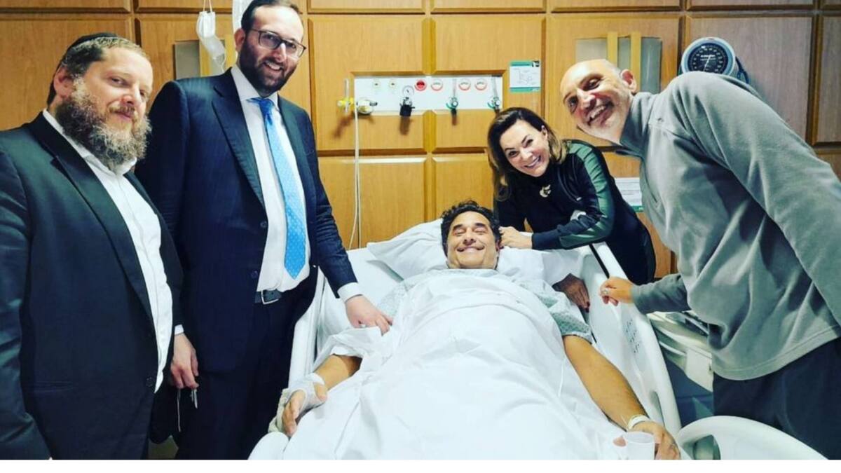Luciano Szafir deitado na cama de hospital, ao lado dos médicos e da mãe Beth Szafir