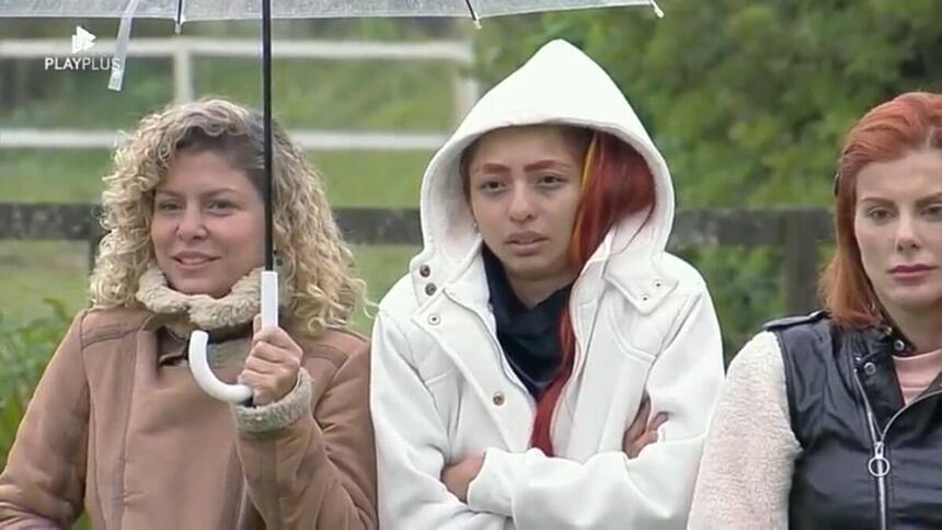 Bárbara segurando um guarda-chuva ao lado de Ruivinha e Deborah
