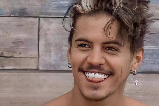 Biel com um sorriso aberto, brincos nas orelhas