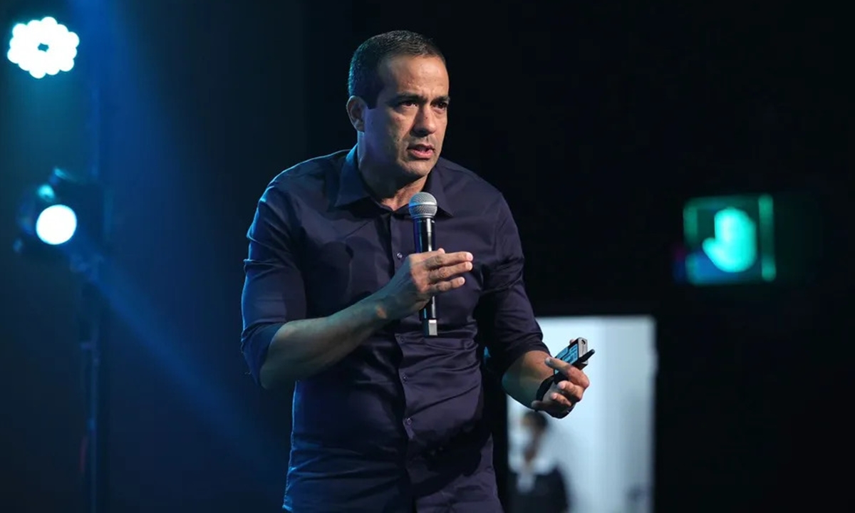 Bruno Reis de camisa social preta, segurando um microfone durante coletiva do Festival Virada Salvador