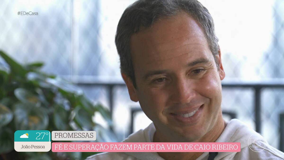 Caio Ribeiro de camisa branca, cabeça baixa, emocionado conversando com a repórter Patrícia Fazan, do É de Casa, da TV Globo