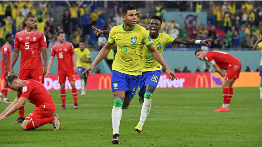 Casemiro e Vinícius Jr de braços abertos e comemorando gol com a camisa do Brasil, na partida contra Suíça na Copa do Mundo