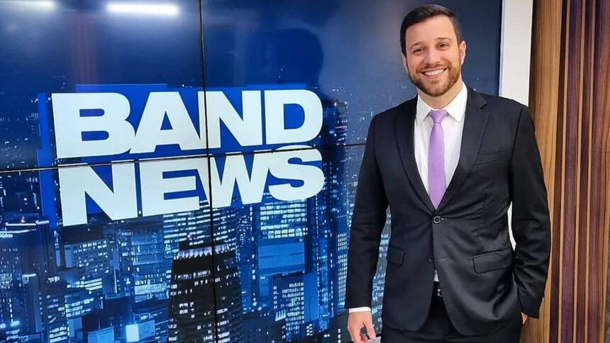 Cassius Zeilmann em foto posada em frente ao telão nos estúdios do BandNews TV