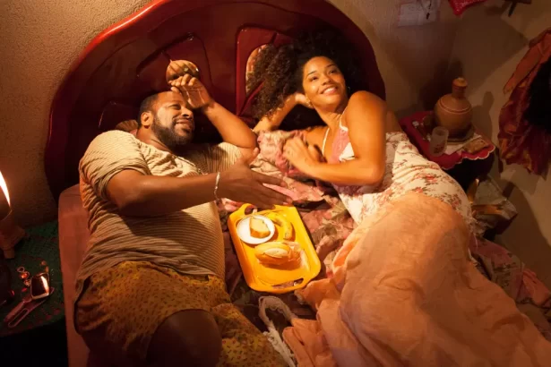 Ailton Graça e Juliana Alves deitados juntos em uma cama, em trecho do filme Correndo Atrás, exibido pela TV Globo na Sessão da Tarde