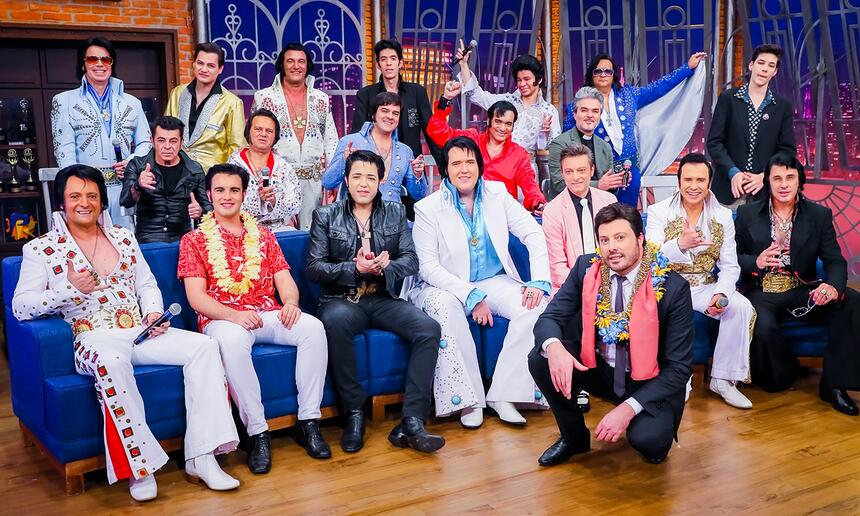 Covers de Elvis Presley sentados num sofá azul ao lado de Danilo Gentili durante gravação do The Noite especial ao aniversário de Elvis Presley