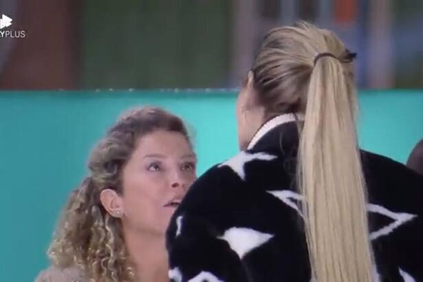 Bárbara sentada discutindo com Deolane que está em pé.