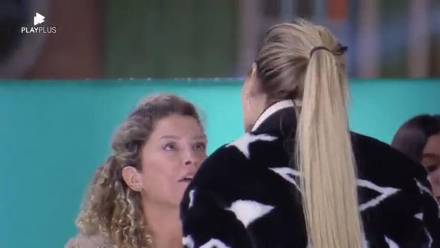 Bárbara sentada discutindo com Deolane que está em pé.