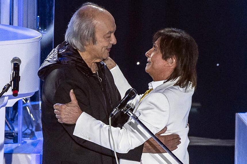 Roberto Carlos de blazer branco abraçando Erasmo Carlos durante gravação do especial de final de ano da TV Globo