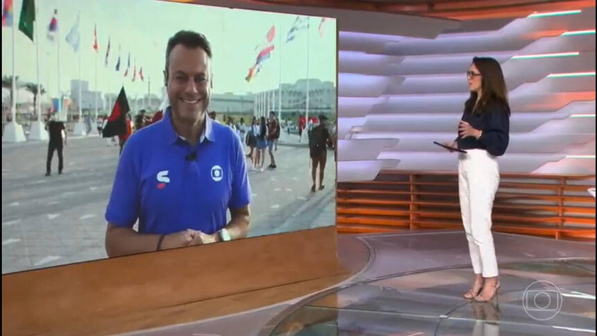 Ana Luiza Guimarães, no estúdio do Bom Dia Brasil, posicionada em frente ao telão, onde o repórter aparece fazendo uma entrada ao vivo do Catar