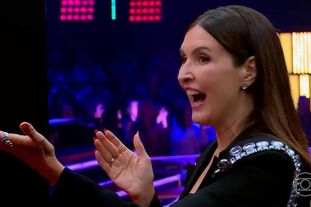 Fátima Bernardes sorrindo, com os braços abertos nos bastidores do The Voice Brasil 11