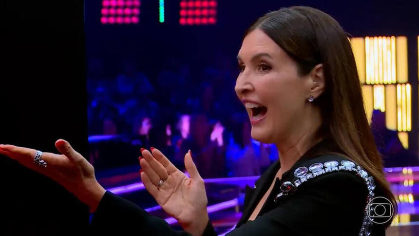 Fátima Bernardes sorrindo, com os braços abertos nos bastidores do The Voice Brasil 11