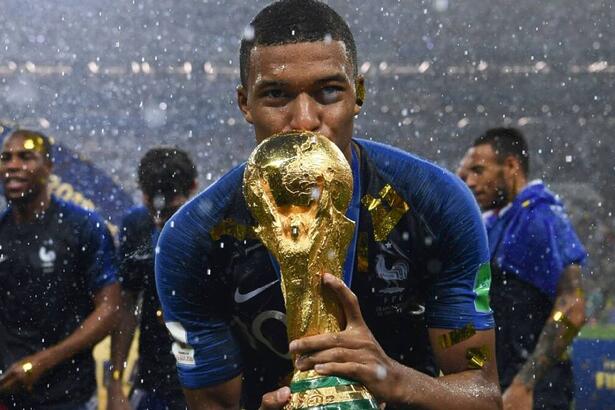 Mbappé, com a camisa da França, segurando a taça de campeão do mundo em 2018