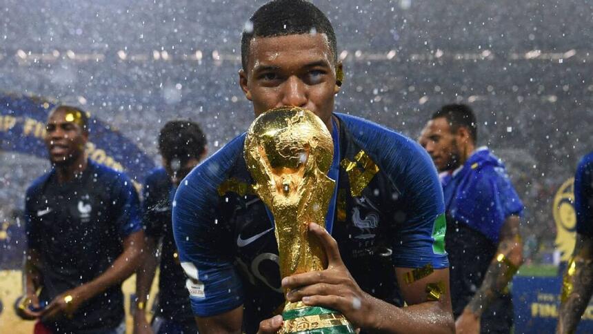 Mbappé, com a camisa da França, segurando a taça de campeão do mundo em 2018