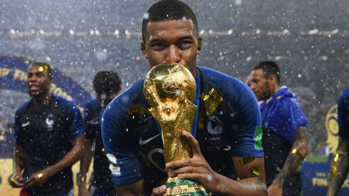Mbappé, com a camisa da França, segurando a taça de campeão do mundo em 2018
