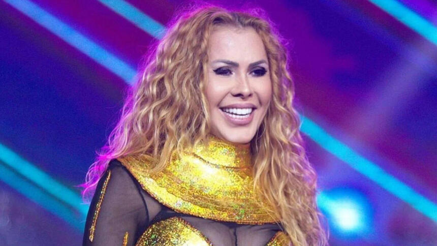 Joelma com um sorriso no rosto, vestindo uma roupa amarela com preto, em trecho de um show